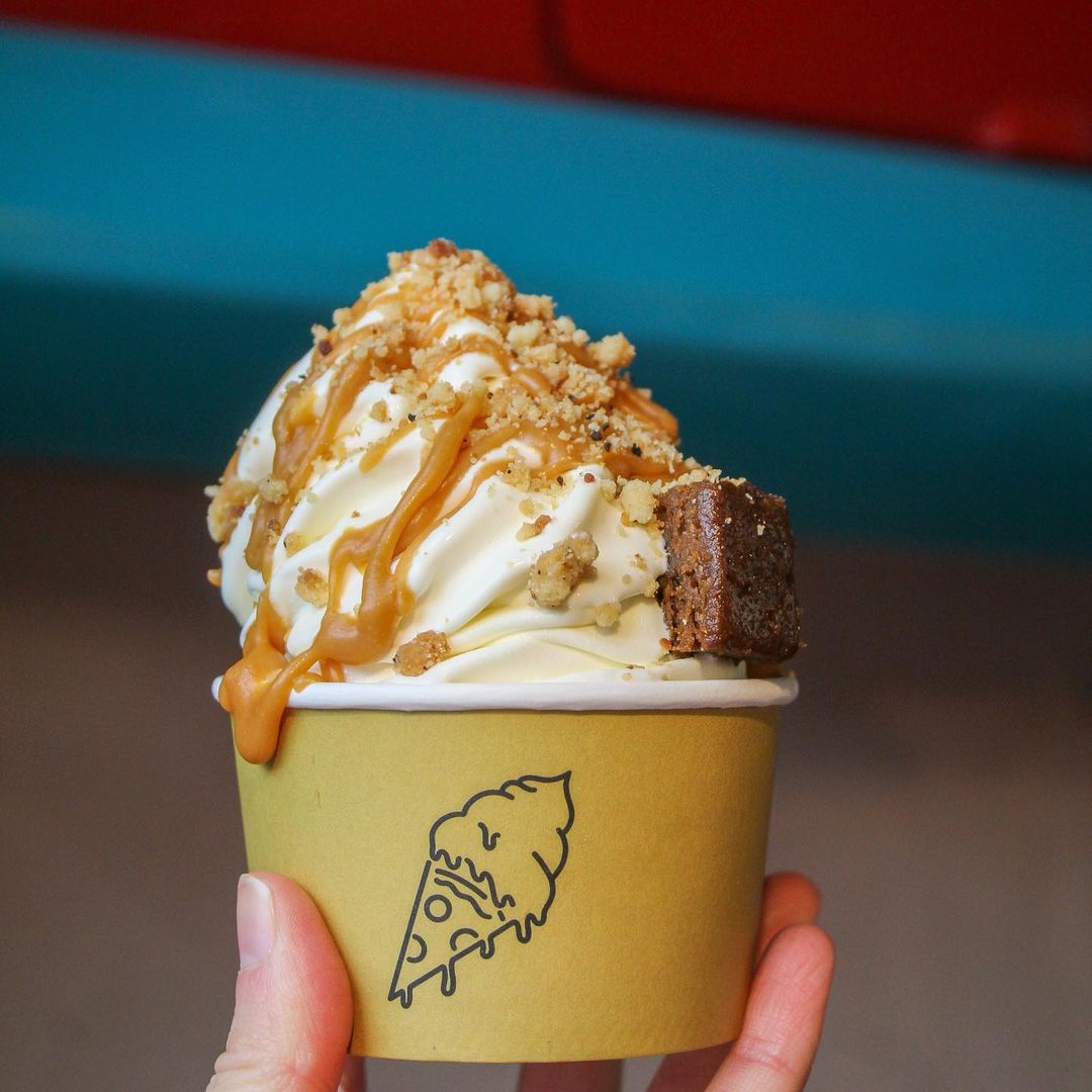 Ice cream cup topped with caramel drizzle, crunchy nuts, and a brownie piece.